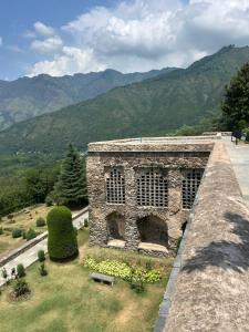 a stone building with mountains in the background at Dilshad Houseboats in Srinagar