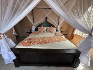 a bedroom with a canopy bed with curtains at Meru Nest Arusha in Arusha +67 photos