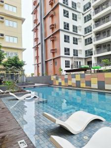 a swimming pool with white chairs and buildings at Studio 7C at One Regis in Bacolod