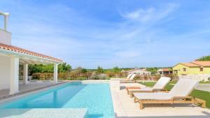 a swimming pool with lounge chairs next to a house at Villa Corsa by Villas Guide in Barban