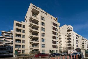 a tall white building with cars parked in front of it at GreenVista 20 minutes by Therme & Airport in Voluntari