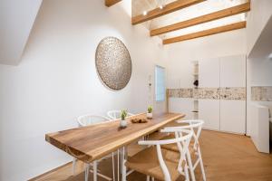 a dining room with a wooden table and white chairs at Infinito Luxury by BarbarHouse in Monopoli