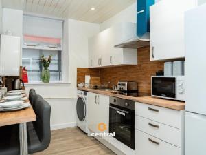 a kitchen with white cabinets and a wooden table at The Bond by CENTRAL SERVICED APARTMENTS - 2 Bedrooms - 3 Double Beds - Walk Away From City Centre & Universities - Walk away from Bus & Train Station & Waterfront - Short & Long Stays Accomodated in Dundee