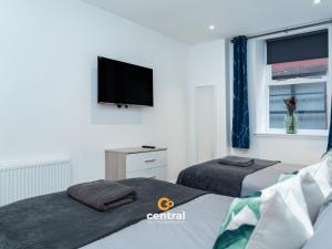 a bedroom with two beds and a flat screen tv at The Bond by CENTRAL SERVICED APARTMENTS - 2 Bedrooms - 3 Double Beds - Walk Away From City Centre & Universities - Walk away from Bus & Train Station & Waterfront - Short & Long Stays Accomodated in Dundee