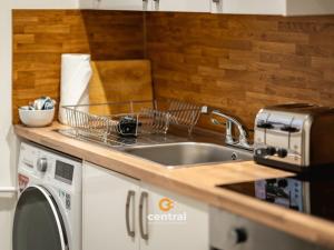 a kitchen with a sink and a washing machine at The Bond by CENTRAL SERVICED APARTMENTS - 2 Bedrooms - 3 Double Beds - Walk Away From City Centre & Universities - Walk away from Bus & Train Station & Waterfront - Short & Long Stays Accomodated in Dundee