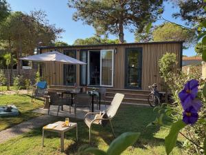 a small house with a table and chairs and an umbrella at Camping Le Calypso 5 étoiles in Torreilles