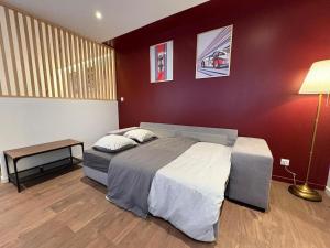 a bedroom with a large bed and a red wall at Le Martini in Chalon-sur-Saône