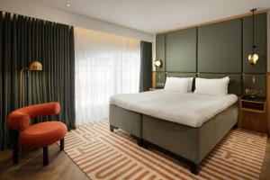 a bedroom with a large bed and a chair at Carlton George Hotel in Glasgow