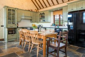 a kitchen with a wooden table with chairs and a black refrigerator at Coach House in Pembroke +32 photos