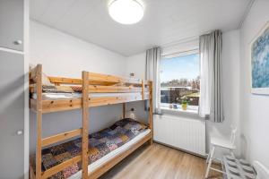 a bedroom with two bunk beds and a window at Feriehus Oluf in Ålbæk