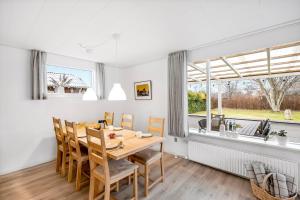 a dining room with a table and chairs and a window at Feriehus Oluf in Ålbæk