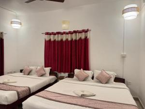 two beds in a room with a red curtain at Townhouse 4bhk Bungalow - TIE Hotels in Pondicherry