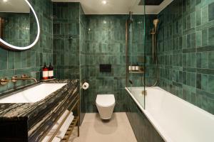 a green tiled bathroom with a tub and a toilet at Carlton George Hotel in Glasgow +15 photos