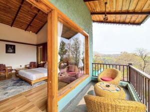 a room with a balcony with a bed and chairs at Corbett Nirvana Resort in Amgarhi
