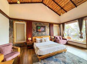 a bedroom with a bed and two chairs at Corbett Nirvana Resort in Amgarhi