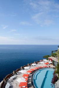 a pool with orange and white umbrellas and the ocean at Il San Pietro di Positano in Positano