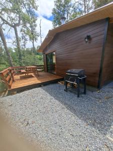 a wooden cabin with a picnic table and a grill at cabaña los ulmos in Lago Ranco