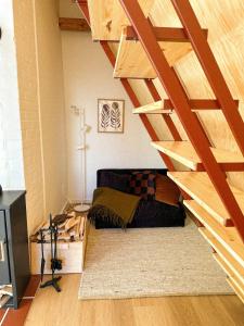 a living room with a couch under a wooden staircase at Lombtér in Pásztó