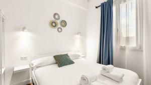 a white bedroom with a bed and a window at Ceramic Rooms in Oristano