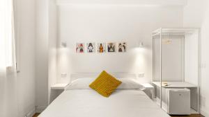 a white bedroom with a bed with a yellow pillow at Ceramic Rooms in Oristano