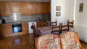a kitchen with wooden cabinets and a table and a dining room at Apartaments Pirinenc in Esterri d'Àneu +17 photos