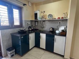 a kitchen with blue and white cabinets and a window at Uttarayan The Homestay in Almora