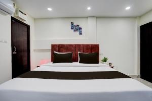 a bedroom with a large white bed with black pillows at Hotel O Khusi Tranquil Domicile in Bhubaneshwar