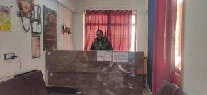 a man standing behind a podium in a room at Hotel Radha Krishana in Māna