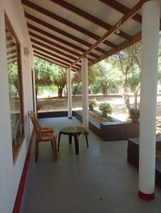 a porch with a bench and a table and a chair at Zendora Resort Yala in Tissamaharama