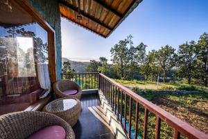 a balcony with wicker chairs and a table on a porch at Corbett Nirvana Resort in Amgarhi