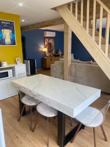 a dining room with a white marble table and chairs at La Grange des Pépettes ! in Saint-Germain-des-Fossés
