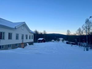 a snow covered yard next to a white building at Huså byskola in Järpen