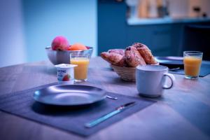 a table with plates of food and two glasses of orange juice at LSWDB Suite Ôna in Bassenge +17 photos