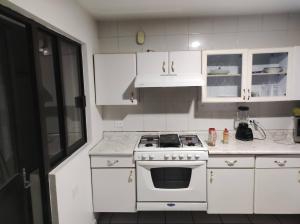 a white kitchen with a stove and white cabinets at Casa al norte in Aguascalientes