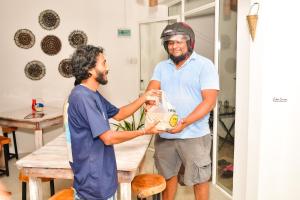 two men are standing in a room holding a bag at ELOP Resturant & Villa in Piyadigama