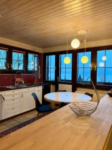 a kitchen with a table and chairs and windows at Chalet Apartment Faulensee in Faulensee