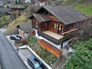 a wooden house with a car parked in front of it at Chalet Apartment Faulensee in Faulensee