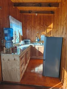 a kitchen with a refrigerator and wooden walls at Astilleros,Dalcahue in Dalcahue