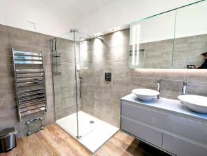 a bathroom with a glass shower and two sinks at 2 Bedroom Unique Converted Constabulary in Nantwich +13 photos