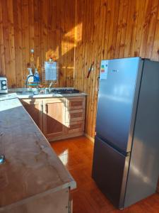 a kitchen with a stainless steel refrigerator and wooden walls at Astilleros,Dalcahue in Dalcahue