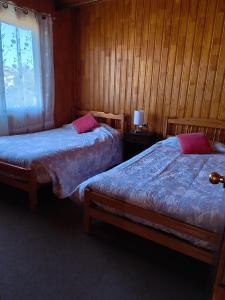 two beds in a room with wooden walls at Astilleros,Dalcahue in Dalcahue