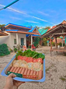 a person holding a tray of hot dogs and lettuce at Yada homestay in Ban Bu Lu