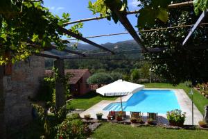 a swimming pool with an umbrella and chairs and a table at Casa de Fujacos in Valença