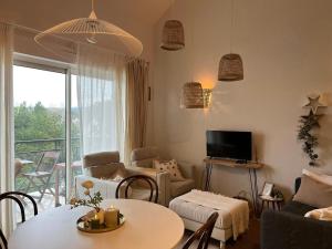 a living room with a couch and a table and a television at Entre Mer et Dunes de Pin in Neufchâtel-Hardelot