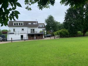 a white house with a green field in front of it at Luxury guesthouse - Eik bij de dijk in Aalst