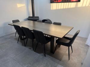 a wooden table with black chairs in a room at The Happy Place in Dawesville