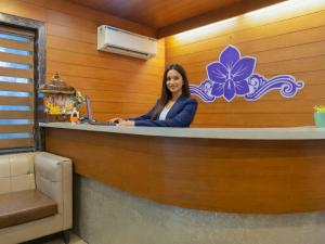 a woman sitting at a counter in a room at Hotel Aerocity Purple Orchid in New Delhi