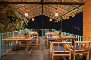 a restaurant with wooden tables and chairs on a balcony at havana stays in Jibhi