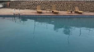 a swimming pool with lounge chairs and the water at The Sixth Abode Farms 5 BHK Villa with Swimming Pool, Turf, Lawn & Indoor Games- Khopoli in Jambhulpāda