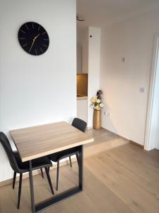 a dining room with a table and a clock on the wall at Level Apartment in Kostajnica +17 photos